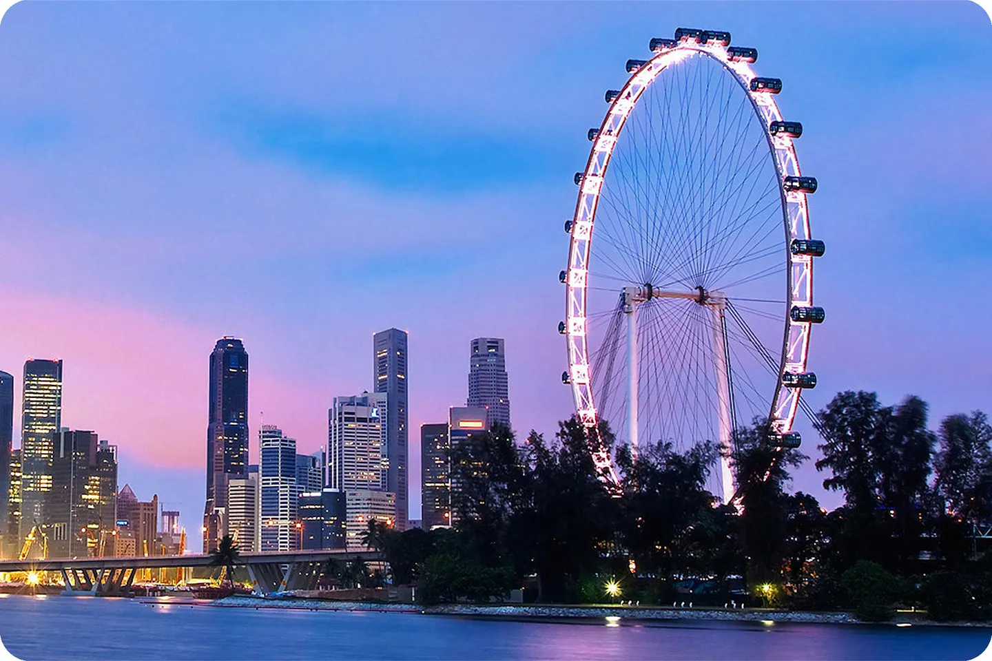 The Singapore Flyer lit at dusk above the city skyline